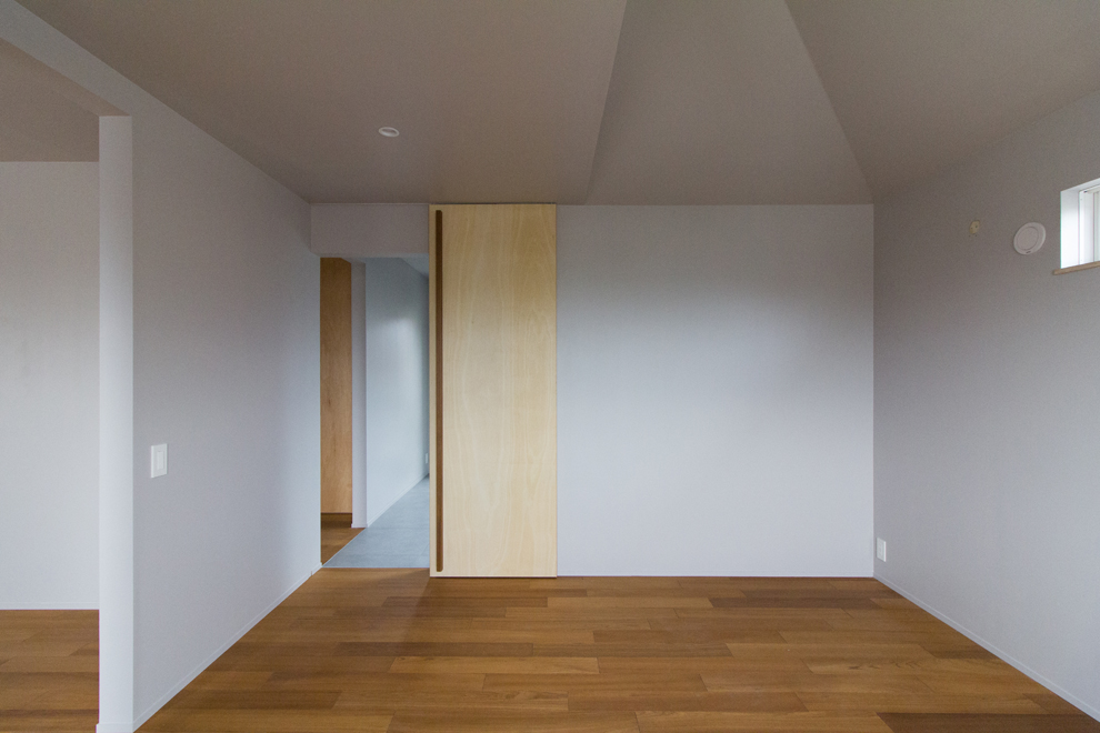 傾斜天井の主寝室　奥に床がタイル貼りの書斎コーナーが続く