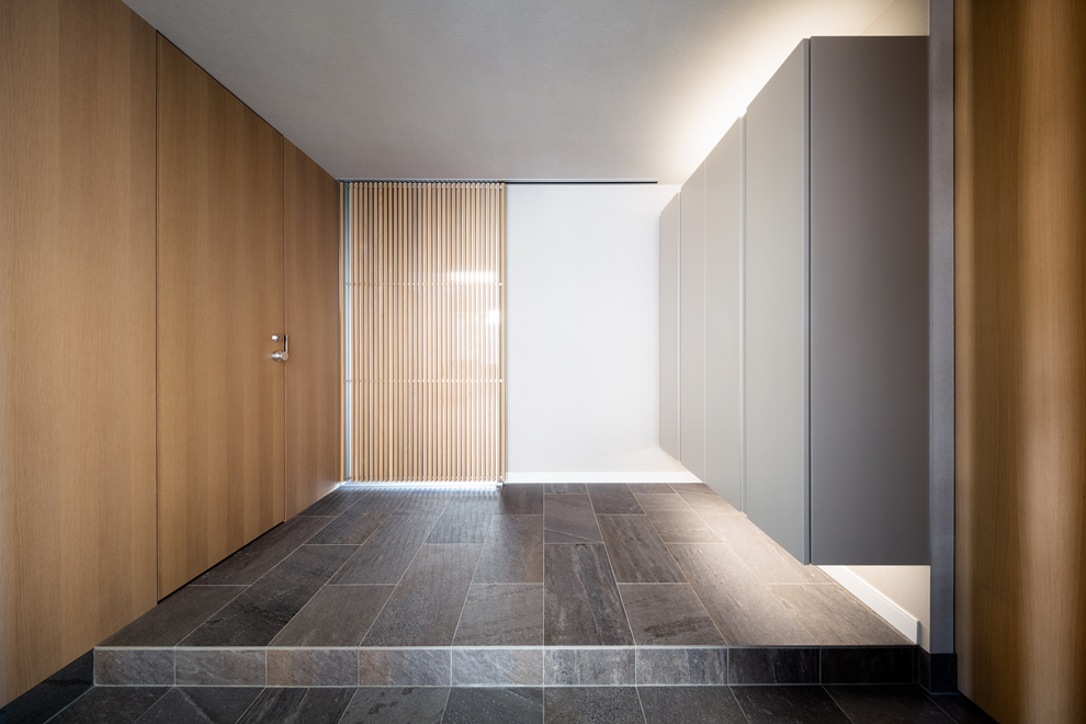 玄関スペース　ルーバー扉はリビングへ　右の木扉はシューズインクロークへ