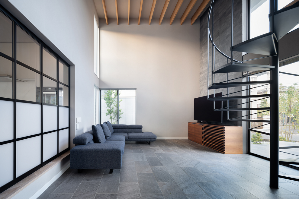 吹抜けと螺旋階段がある大空間のリビング　奥にバステラスの植栽が見える