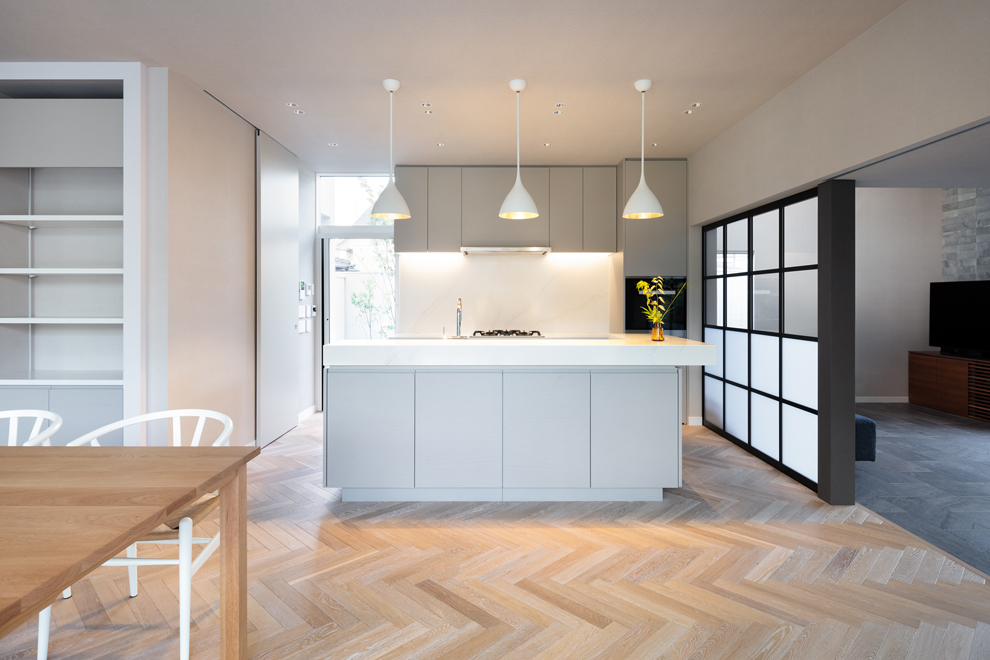 二型のアイランドキッチン　左側にはパントリー、ランドリー、洗面と家事動線が続く扉